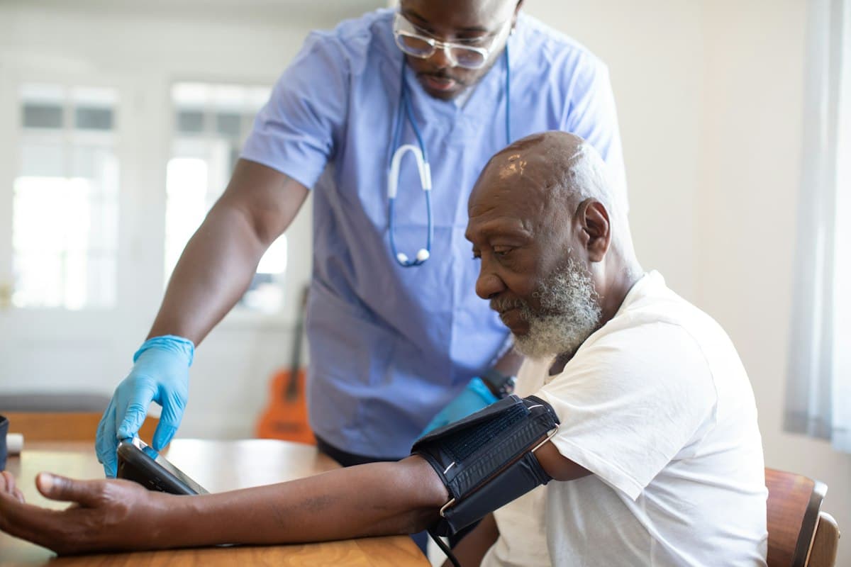A clinician taking an older patient's blood pressure in an exam room