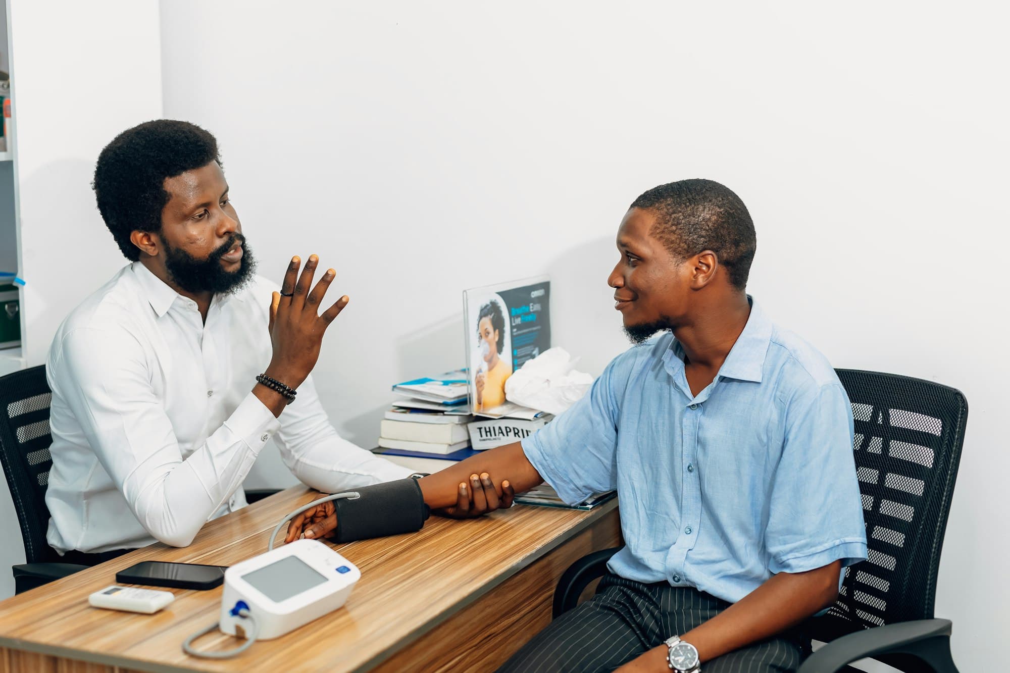 A physician talking with a patient during a blood pressure check at his desk